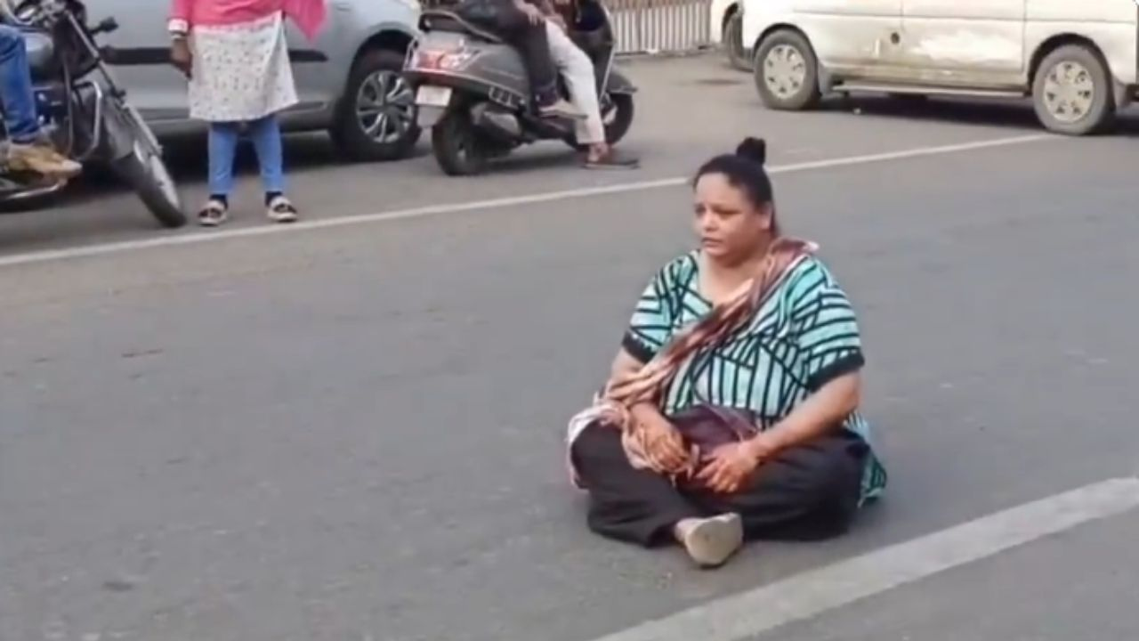 women sitting on road । Photo Credit: Video Grab